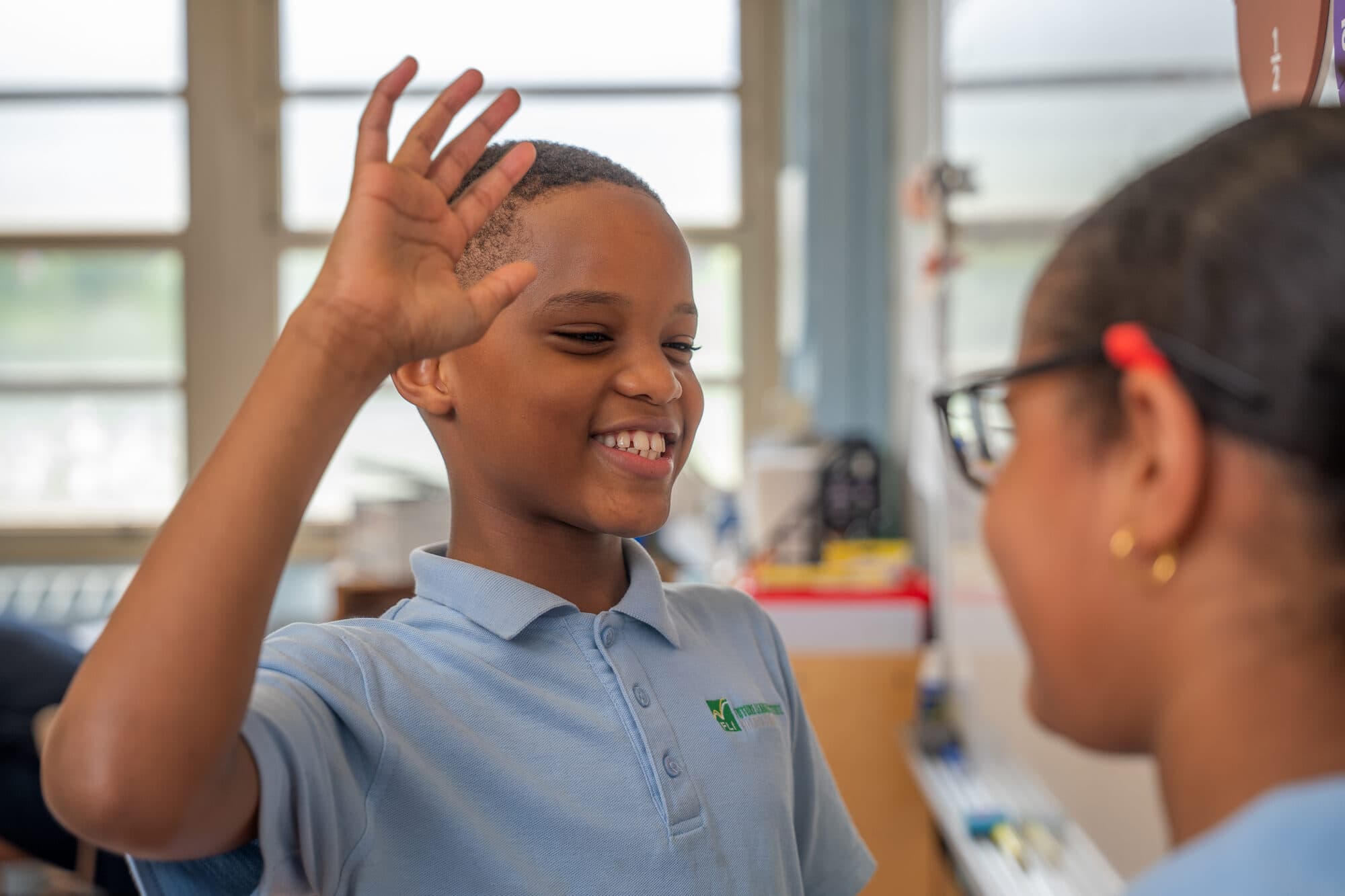 An FLI student with a hand raised during an Extended Day session.